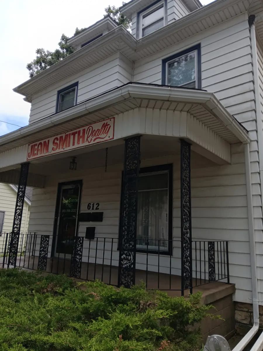 Cleaned and repainted storefront exterior with the restored iron entry railing and sign.